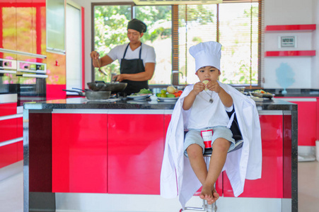 可爱的小泰国男孩在厨师的帽子和外衣坐在一个高的 c