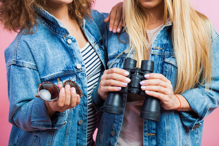 两个美女在牛仔裤夹克太阳镜和双筒望远镜