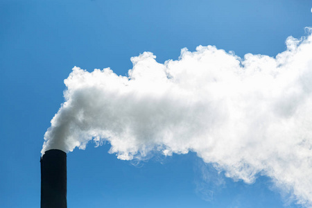 白烟从烟囱于背景的蓝蓝的天空。空气污染和环境。温室气体效应。环境灾害