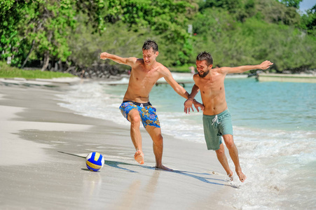 在阳光明媚的热带海滩踢足球的朋友