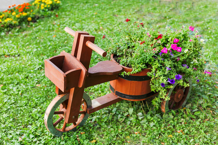 作为木制自行车被塑造的花坛。矮牵牛花卉与园林装饰