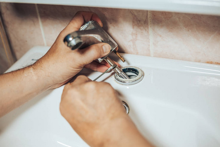 人在卫生间里水龙头上的服务和修理漏水老龙头.那人擅老龙头照片