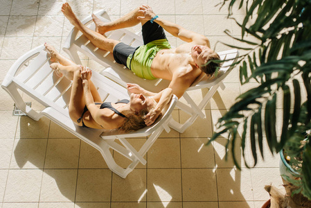 的年轻夫妇放松在太阳床附近的游泳池。女孩和男孩在暑假的假期。完美的身体, 惊人的曲线, 日落
