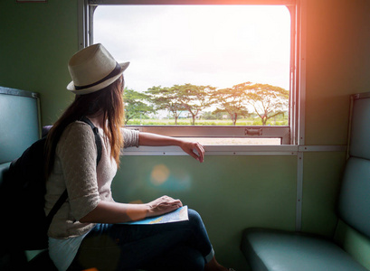 年轻漂亮的女人坐坐在窗边看着窗外的经典火车旅行。度假和旅游的概念