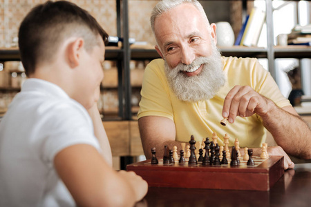 迷人的老人移动一个棋子和孙子一笑