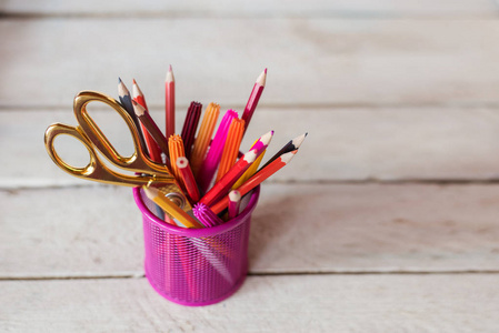 剪刀和彩色铅笔的紫黄色粉红色红色和橙色在固定杯木桌和背景。Copyspace 学校概念
