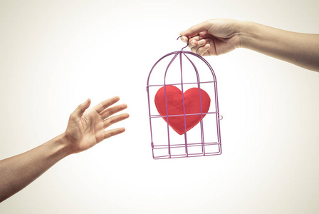 禁止的笼笼中的小鸟与一颗红色的心照片
