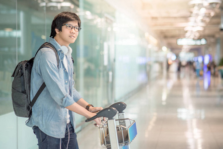亚洲年轻男子在机场航站楼小车式行走