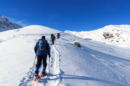 一群人徒步雪鞋和与蓝蓝的天空，在奥地利洛尔阿尔卑斯山雪全景