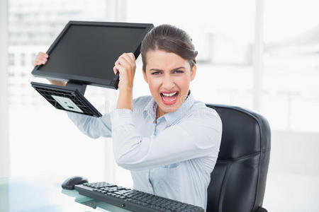 恼火的古板棕色头发的女商人扔电脑屏幕