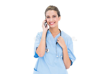 微笑的棕色头发护士穿着蓝色的衣服打电话