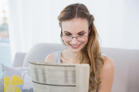 坐在沙发上看报纸的快乐年轻女子