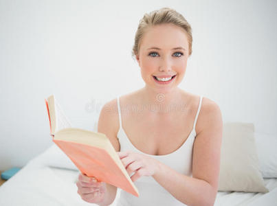 自然微笑的金发女郎拿着一本书