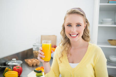 微笑可爱的金发女郎拿着一杯橙汁