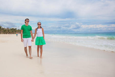 阳光明媚的海滩上漫步的年轻夫妇