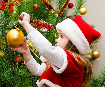 小女孩戴着圣诞帽装饰圣诞树
