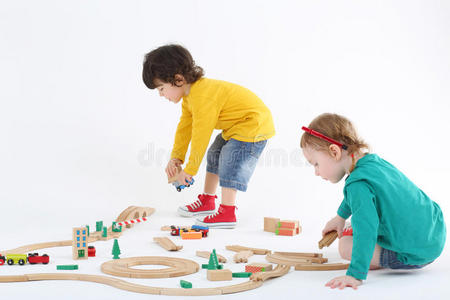 专注的小男孩和小女孩用木制部件建造铁路
