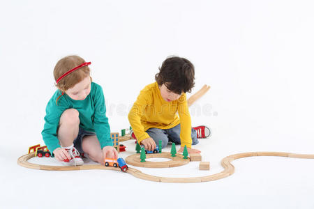 小可爱的女孩和男孩在木制铁路上滚动火车