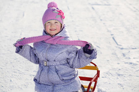 穿着暖和的微笑女孩戴着粉色围巾和帽子抬头看照片