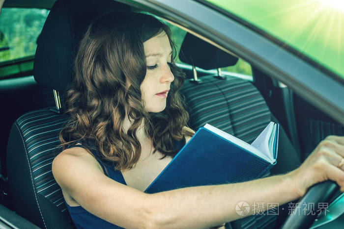 女司机在车里看书.分心和危险驾驶.违反交通规则