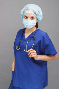 女医生在蓝色医疗制服，与脖子上的听诊器和面具的脸
