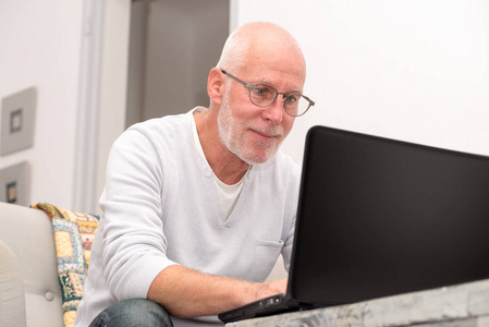 老人坐在沙发上的笔记本电脑