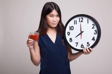 年轻的亚裔女子和番茄汁和时钟