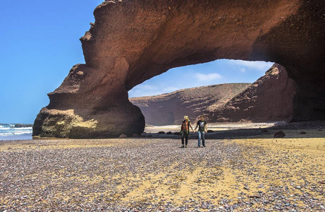 一个男人和女人在摩洛哥 Legzira 附近的海滩漫步