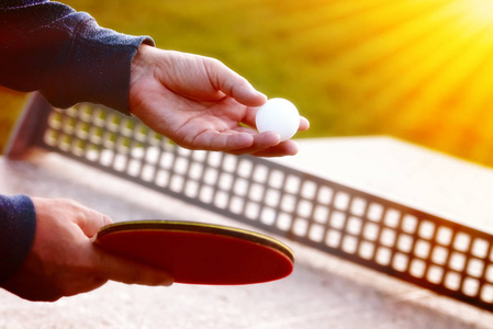 密切的网球球员手联系自然背景网球球拍在阳光明媚的日子。一名男子在乒乓球服役的特写镜头。室外网球场表玩图片