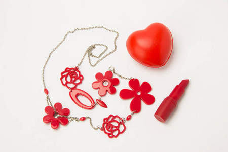 红色的口红 心和项链与白色背景上的花朵