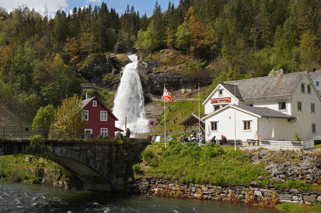 Steinsdalsfossen 瀑布中半胱氨酸在河景观与叶栅环绕山和传统的挪威，斯堪的纳维亚的房子