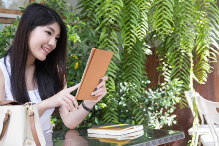 亚洲女人坐在户外咖啡馆。年轻女性成人使用数字