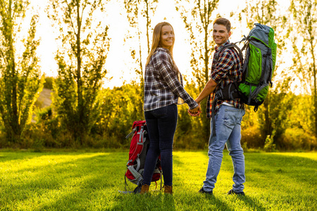 年轻夫妇背着背包的草地上