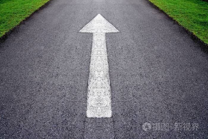 通过绿色灰色沥青道路上白色前进箭头标志