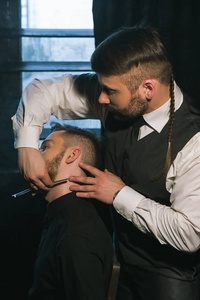 时尚理发师剃须男性与锋利的剃刀