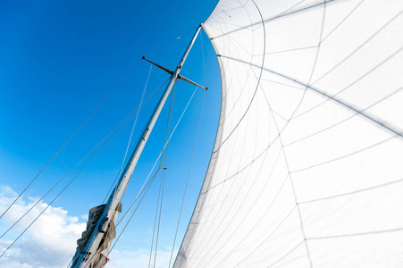 白色的游艇航行在阳光下蓝色多云的天空背景上