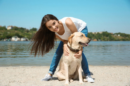 在河附近的黄色猎犬休息的少妇