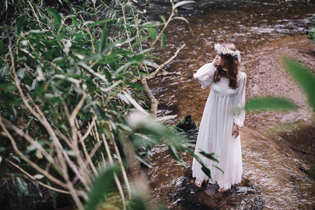 美丽的女孩在一条河附近的白色连衣裙