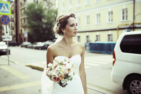 美丽的年轻新娘的画像在婚礼白色礼服摆在街上