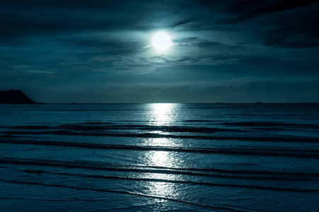 色彩斑斓的天空乌云密布，皎洁的月亮在海景。宁静自然背景