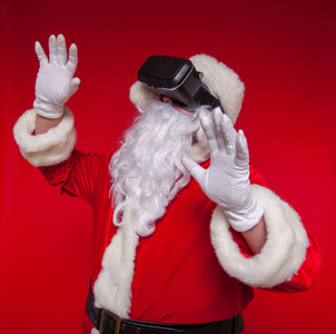 圣诞老人戴着虚拟现实的护目镜, 在红色的背景。圣诞节