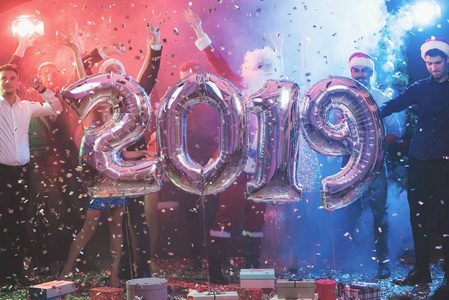 青年人在新年党是摆在与大闪闪发光的充气球以数字的形式2019