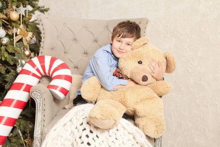 可爱的小男孩带着玩具和礼物围着圣诞树独自坐着