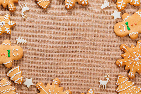 圣诞节姜饼饼干自制和新年装饰在桌子上的粗麻布桌布。圣诞快乐明信片具有可用空间的框架