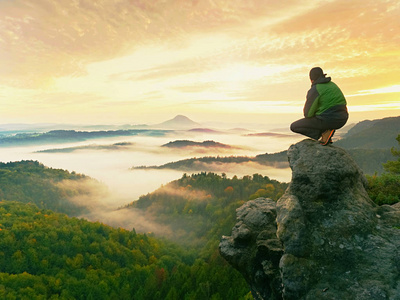 徒步旅行者在山顶休息。男子坐在尖锐的山顶和欣赏壮观的景色