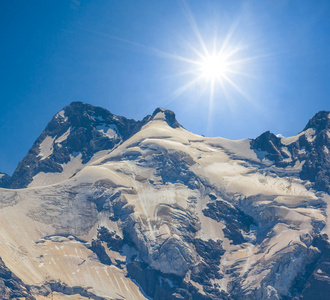 在闪耀的阳光下, 在雪中登上山顶