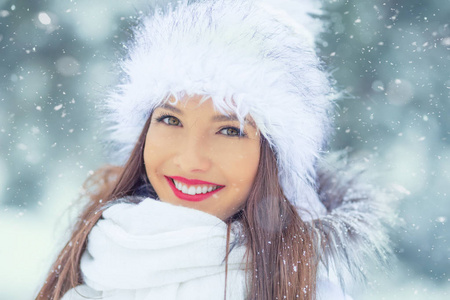 美丽微笑的年轻女子穿着暖和的衣服。冬季雪中画像的概念