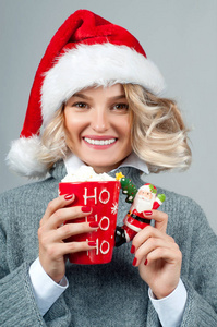 圣诞节和新年。戴着圣诞老人帽子的女人拿着一杯咖啡