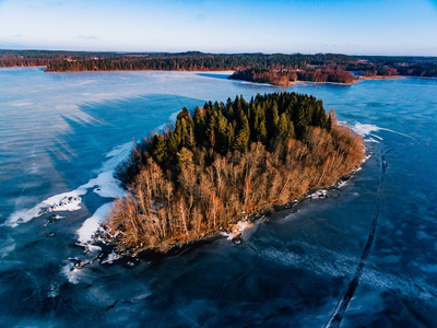 空中鸟瞰的冬季雪森林和冰冻湖从上面捕获的无人机在芬兰