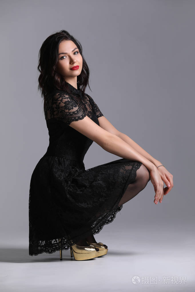 穿高跟鞋的女士蹲下.灰色背景.photographie retouchee